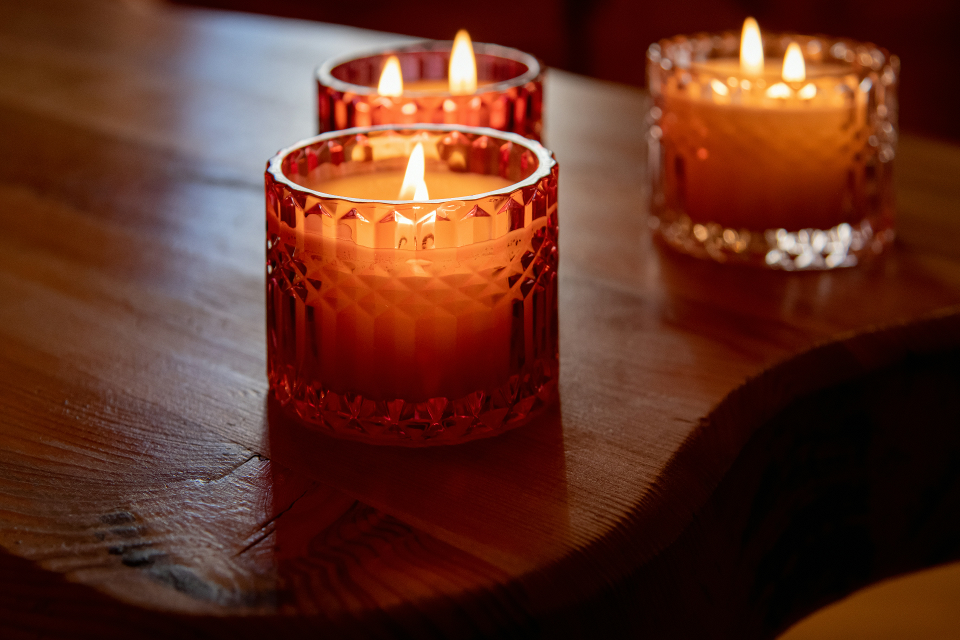 Warm candlelight glowing in faceted glass on a wooden table